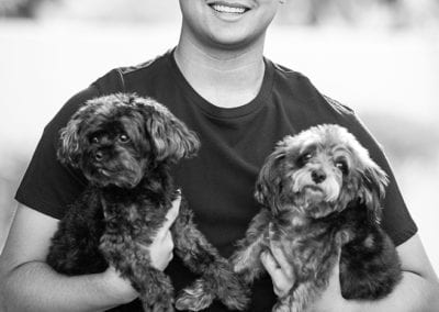 monochrome photo of boy holding 2 puppies