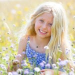 blond girl in a meadow holding a flower