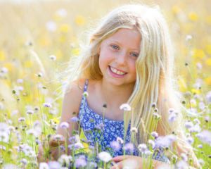 blond girl in a meadow holding a flower