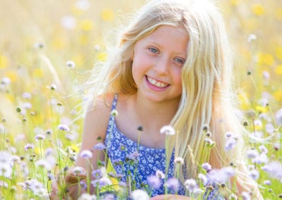 blond girl in a meadow holding a flower