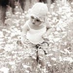 monochrome photo of toddler picking a flower in a meadow