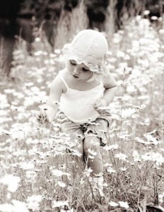 monochrome photo of toddler picking a flower in a meadow