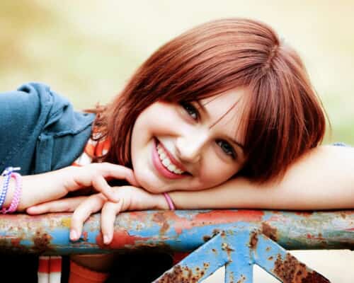 girl with red hair leaning on a gate