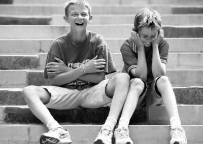 monochrome photo of 2 boys sitting on steps and sharing a joke