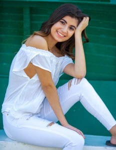 portrait of a senior college girl sitting by a green boat