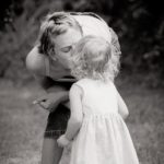 monochrome photo of mother kissing her child in a garden