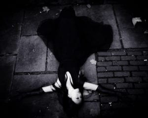 photo of woman wearing long leather gloves lying in a street