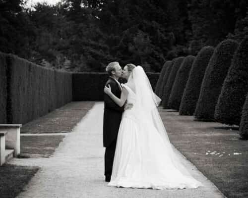 Black and white photo of a recently married couple kissing in a beautiful garden